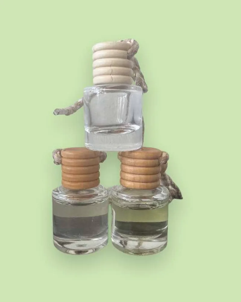 Three hanging car freshener bottles with wooden caps